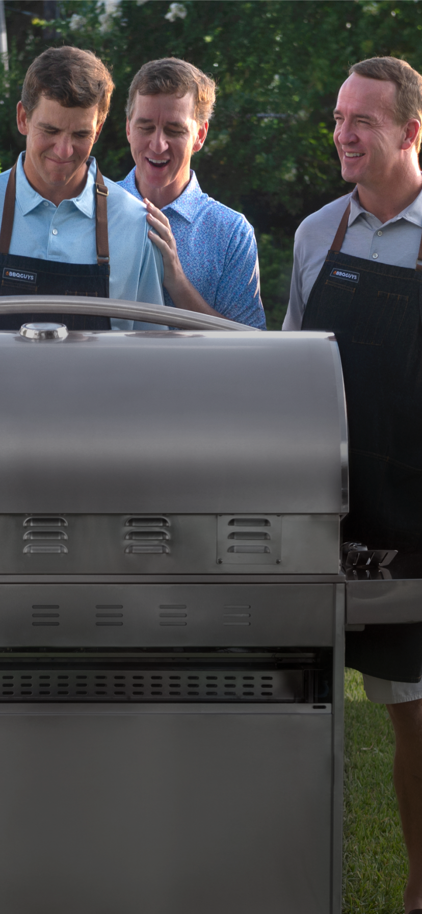 The Manning family standing over a grill.