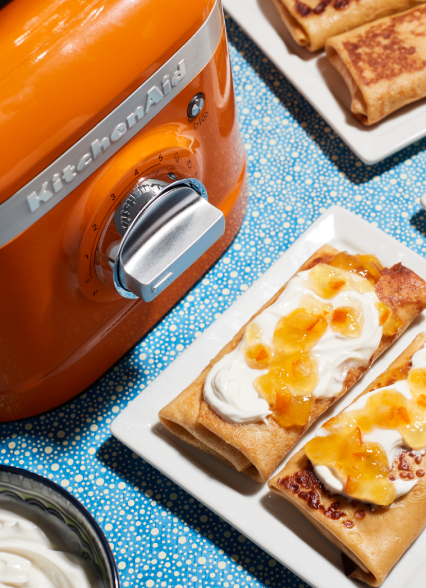 The base and control knob of a KitchenAid blender with pastries next to it.