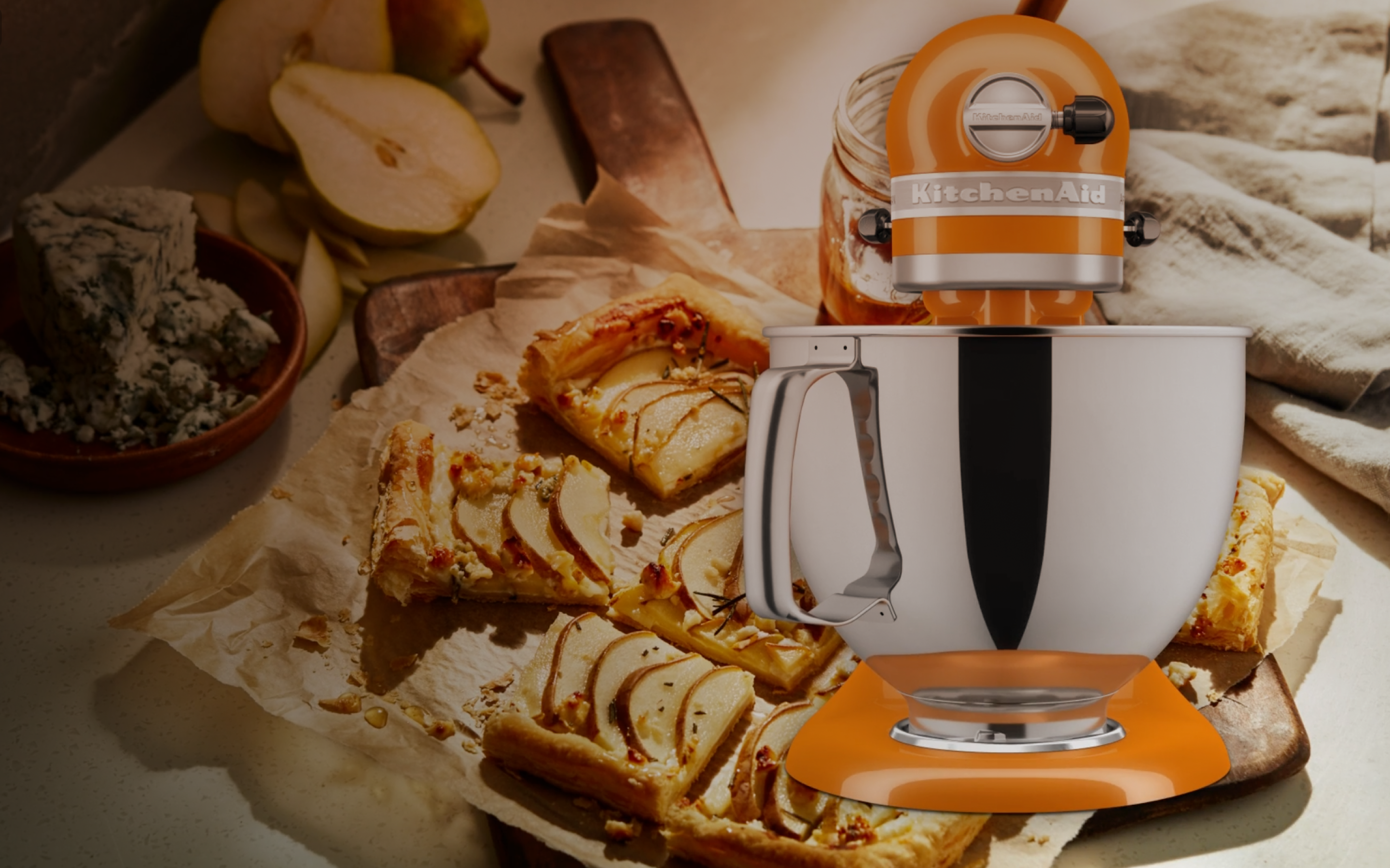 A KitchenAid stand mixer over baked goods and halved pears.