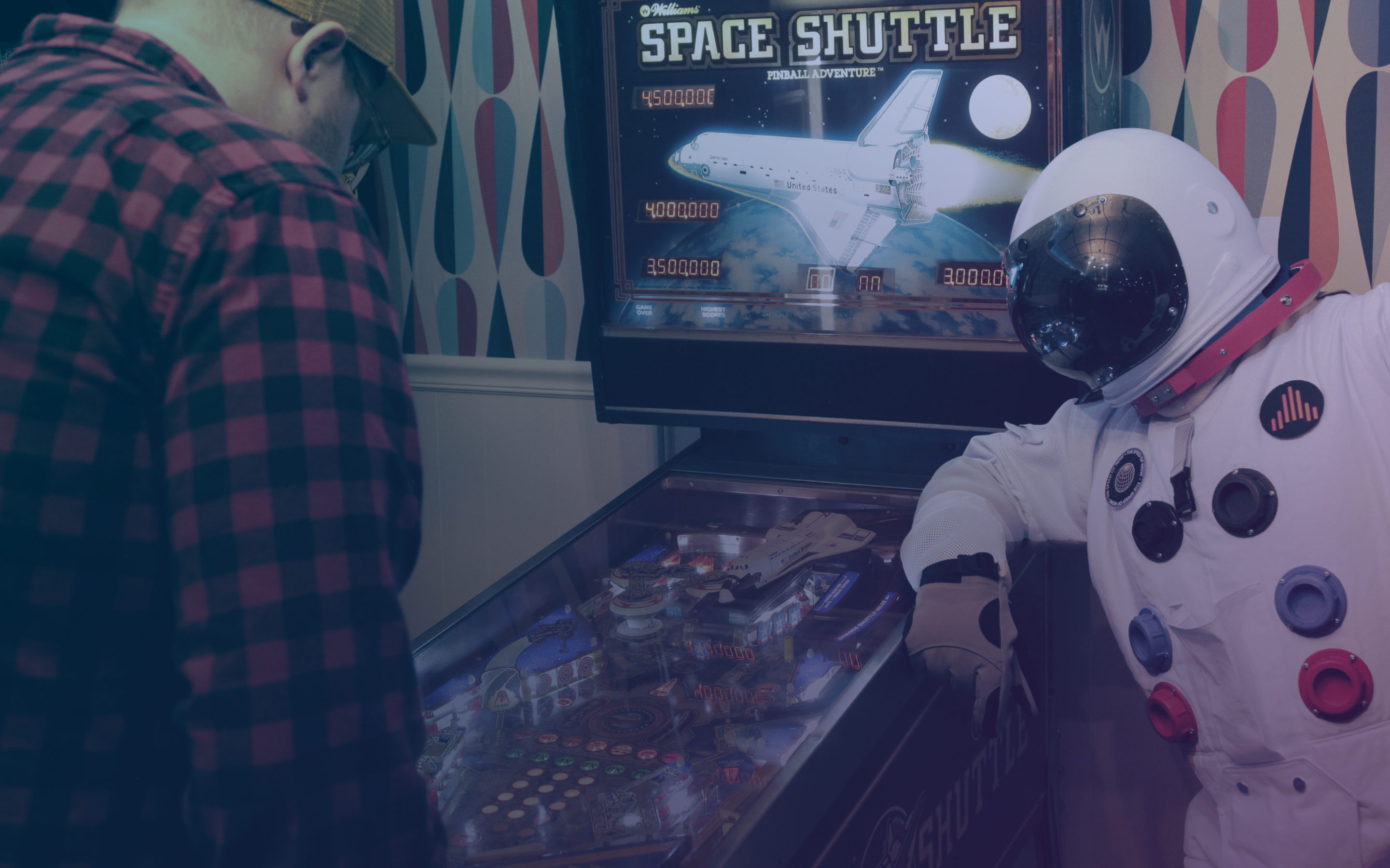 An astronaut leaning on a pinball machine.
