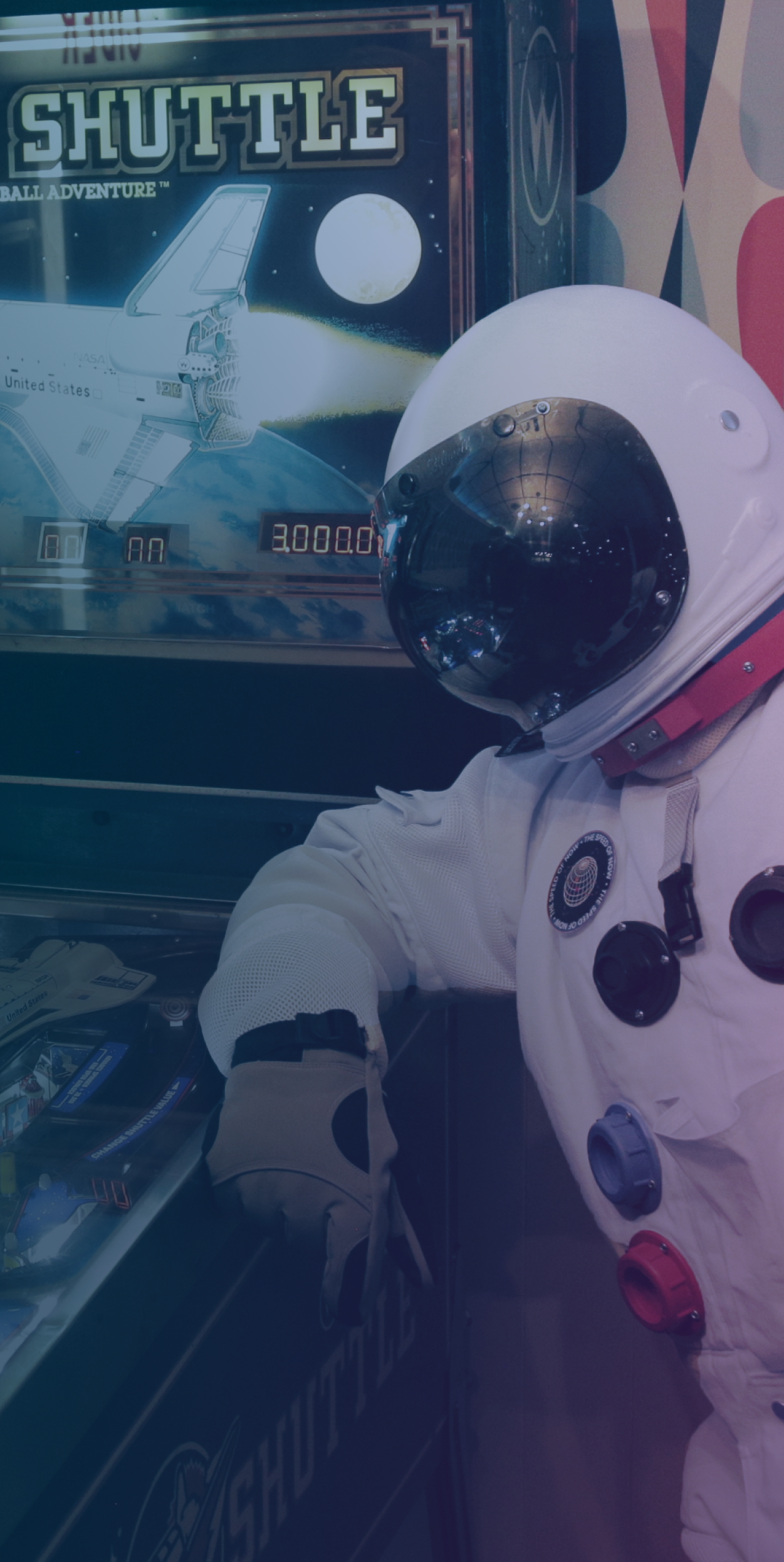An astronaut leaning on a pinball machine.
