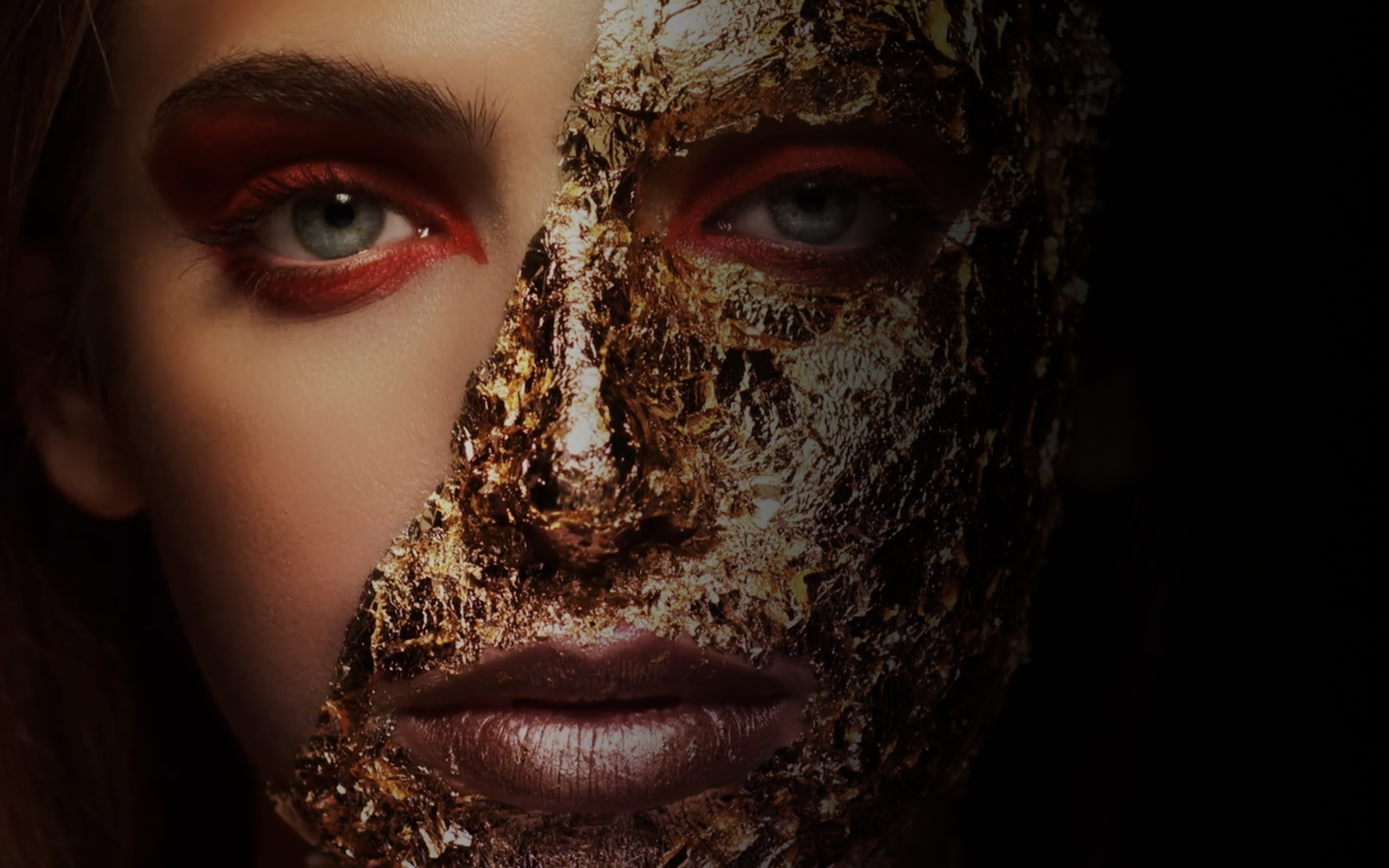 A woman with golden foil covering half her face.